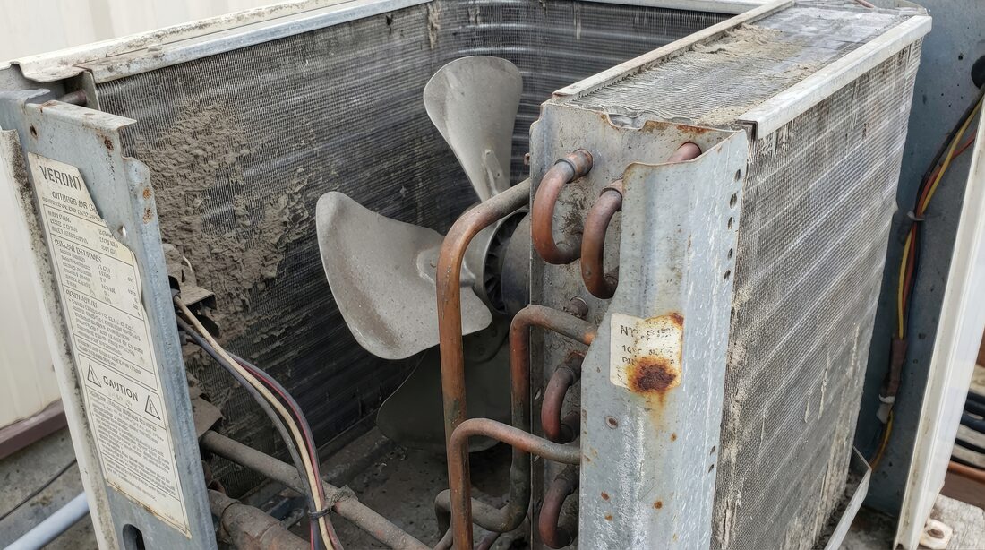 熱とほこりで劣化した屋外空調機の室外機（ファン・銅管にサビと汚れ）